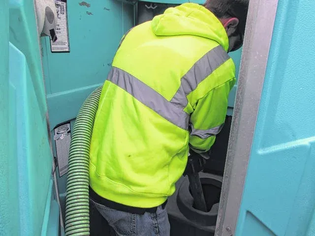 Portable toilet unit being pumped clean with the vacuum hose